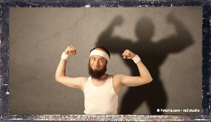 A funny young guy posing in front of brown background with muscular body shadow reflected on the wall